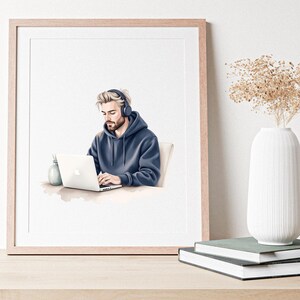 May include: A framed watercolour print shows a person in a blue hoodie and headphones using a laptop. A small vase and pen holder are on the desk. The print is on a wooden table, with a white vase and books in the background.