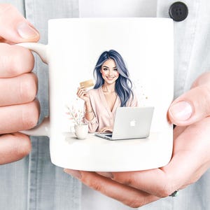 May include: White ceramic mug with a watercolour illustration of a woman with blue hair holding a credit card and using a laptop. A small cup and floral arrangement are also depicted. The mug is held by a person.