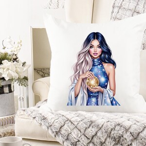 May include: White square throw pillow featuring a digital illustration of a woman with blue and silver hair, holding a golden orb. The woman is wearing a blue dress with a starry pattern. The pillow is on a white couch.
