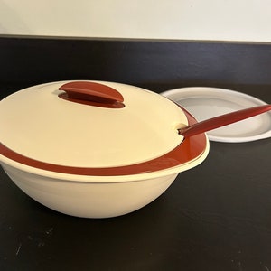 May include: White serving bowl with a red rim and lid. The lid has a red handle. A red serving spoon is included.