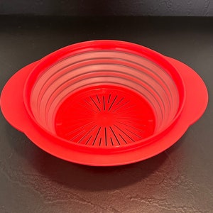 May include: A red plastic colander with a white inner strainer and two handles. The colander is designed to be stackable and has a circular shape.