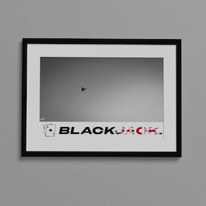 May include: A black and white photograph of an aircraft flying in the sky. The photo is framed in a black frame with a white mount. The bottom of the frame has a sticker with two playing cards and the text "BLACKJACK" with the letters "JACK" in the colours of the Union Jack flag.