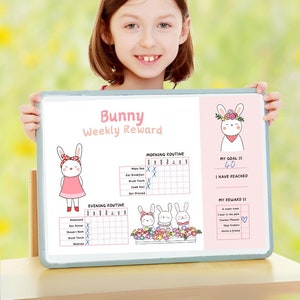 Pode incluir: Um quadro branco de apagamento a seco com um tema de coelho rosa. O quadro tem um gráfico de recompensas semanais com seções para as rotinas da manhã e da noite. O gráfico inclui caixas de seleção para tarefas como fazer a cama, escovar os dentes e jantar. O quadro também tem uma seção para definir uma meta e uma recompensa por atingir a meta. O texto no quadro diz "Bunny Weekly Reward", "Morning Routine", "My Goal Is 40", "I Have Reached", "Evening Routine", e "My Reward Is".