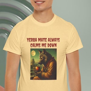 Peut inclure: Un t-shirt jaune avec le texte "Yerba Mate Always Calms Me Down" et un loup de dessin animé buvant dans une gourde.