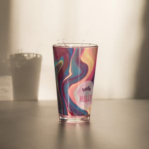 Puede incluir: Un vaso de vidrio colorido con un patrón de remolino y una pegatina que dice "hello HELLO".