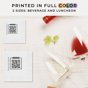 Puede incluir: Dos servilletas blancas con un código QR en blanco y negro que dice "SCAN ME" y el texto "Business Name" impreso en ellas. Las servilletas están sobre una superficie de madera blanca con dos copas de vino y una botella de vino.