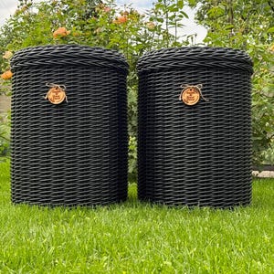 Può includere: Due cesti portaoggetti cilindrici in vimini nero intrecciato con coperchi abbinati. Ogni cesto presenta un'etichetta rotonda in legno legata con spago, che riporta il testo Garden & Home Decor. I cesti hanno una finitura in vimini sintetico.