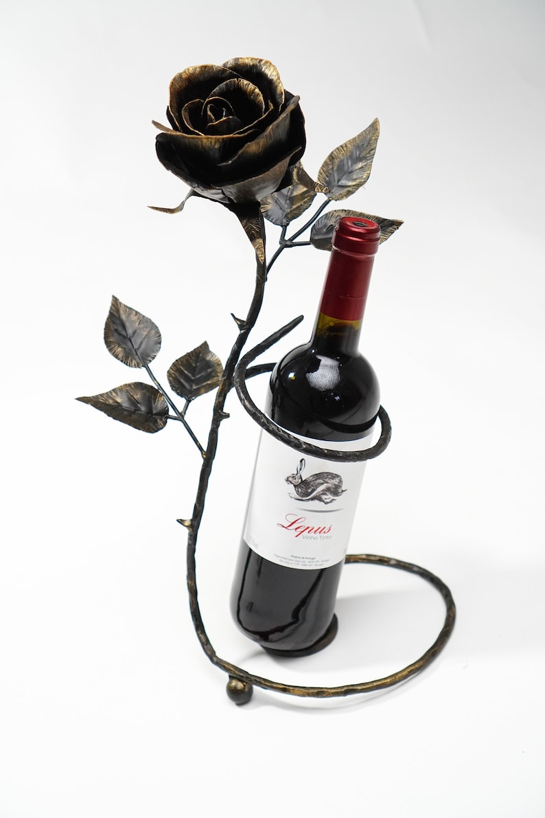 May include: A black metal wine bottle holder shaped like a rose with a bottle of red wine inside. The bottle label says "Lepus Argentina".