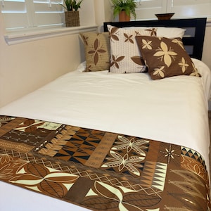 May include: A brown and white patterned bed runner with a geometric design. The runner is on a white bed with brown and white patterned pillows.