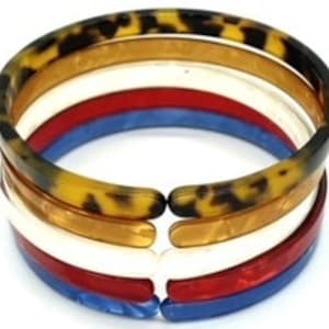 Può includere: Set di quattro braccialetti rigidi colorati. I braccialetti sono in plastica e hanno un motivo a tartaruga. I braccialetti sono impilati uno sopra l'altro, con il braccialetto superiore di colore marrone chiaro, il secondo braccialetto di colore bianco, il terzo braccialetto di colore rosso e il braccialetto inferiore di colore blu.