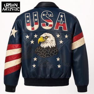 Pode incluir: Casaco de couro azul marinho com gola e punhos pretos. As costas apresentam um grande gráfico de águia, a palavra "USA" em vermelho e branco e estrelas brancas. As mangas têm listras vermelhas e brancas e uma estrela branca.