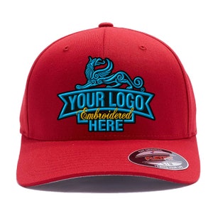 Może przedstawiać: Czerwona czapka bejsbol&oacute;wka z zakrzywionym daszkiem. Czapka posiada niestandardowe haftowane logo w kolorze niebieskim i złotym z napisem "YOUR LOGO Embroidered HERE". Z boku znajduje się etykieta Flexfit.