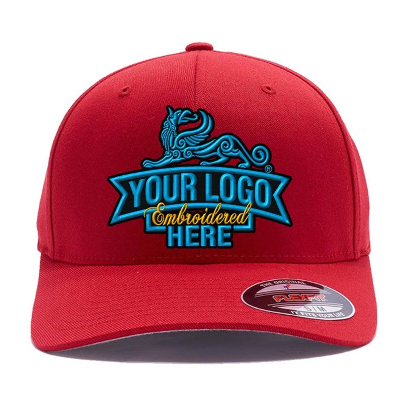 Może przedstawiać: Czerwona czapka bejsbol&oacute;wka z zakrzywionym daszkiem. Czapka posiada niestandardowe haftowane logo w kolorze niebieskim i złotym z napisem "YOUR LOGO Embroidered HERE". Z boku znajduje się etykieta Flexfit.
