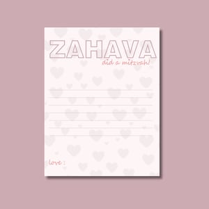 May include: A white card with a pink heart pattern and the text "ZAHAVA did a mitzvah!" in black outlined letters. The text "love:" is written in pink at the bottom of the card.