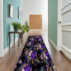 May include: A black and purple runner rug with a skull and floral pattern. The rug is in a hallway with a wooden floor.