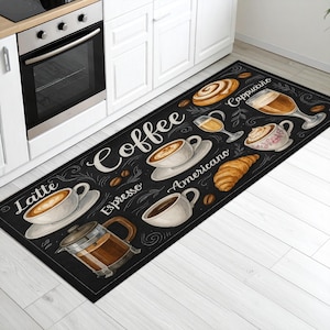 Könnte beinhalten: Schwarzer rechteckiger Küchenteppich mit Illustrationen zum Thema Kaffee. Enthält Bilder von Kaffeetassen, einer French Press, einem Croissant und dem Wort "Coffee" in weißer Schrift. Der Teppich liegt vor einem weißen Küchenschrank und Backofen.