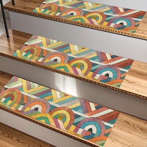 Può includere: Gradini colorati con un design geometrico. I gradini presentano un motivo ripetuto di linee curve e rette nei toni dell'arancione, giallo, blu, verde e viola. I gradini sono rettangolari e si adattano alle scale in legno.