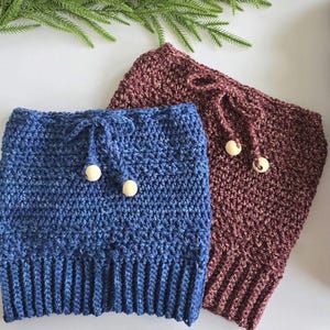 May include: Two crocheted leg warmers with wooden toggles. One is blue and the other is burgundy.
