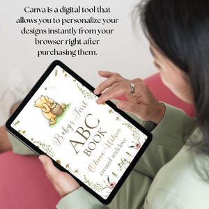 K&ouml;nnte beinhalten: Ein digitales Tablet zeigt ein personalisiertes erstes ABC-Buch f&uuml;r Babys mit einer Illustration von Winnie Puuh. Der Buchumschlag zeigt ein Blumenmuster und den Text "Baby's First ABC Book Olivia Wilson created with love."