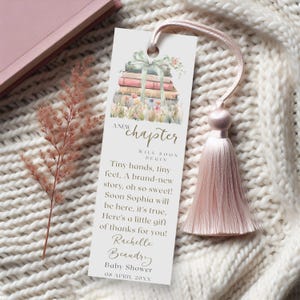 Pu&ograve; includere: Un segnalibro rosa con un motivo floreale e un fiocco. Il segnalibro contiene una citazione su un nuovo capitolo che inizia e una pila di libri con un nastro. Il testo dice "A new chapter will soon begin. Tiny hands, tiny feet. A brand-new story, oh so sweet! Soon Sophia will be here, it's true. Here's a little gift of thanks for you! Rachelle Beaudry Baby Shower 08 APRIL 20XX"