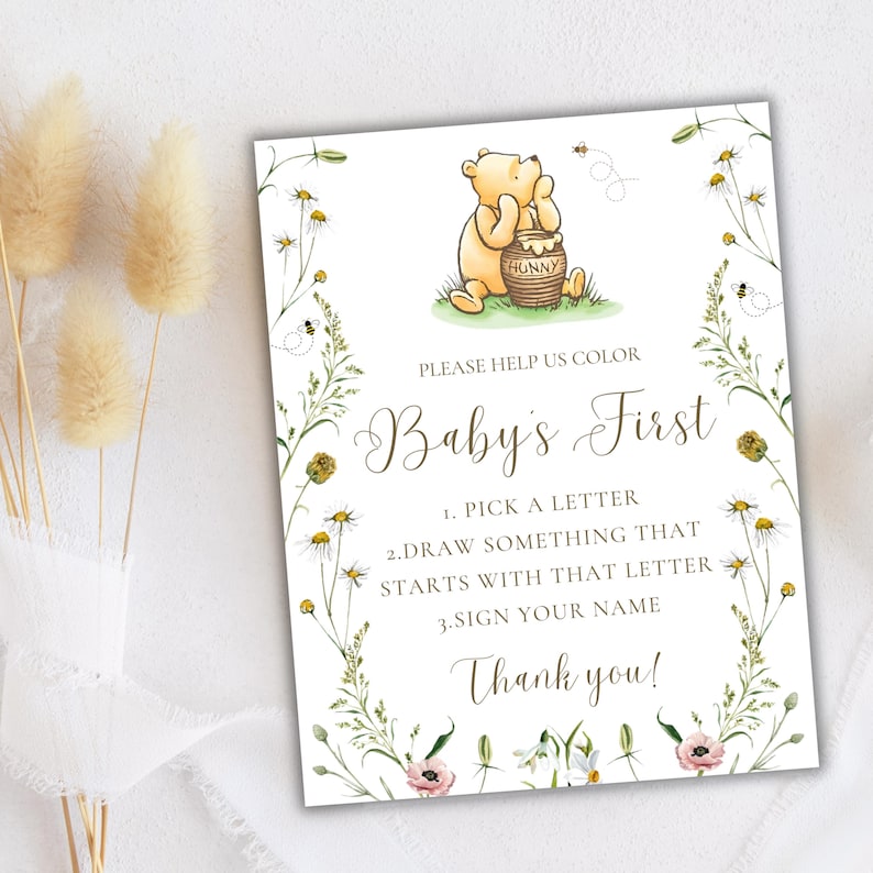 K&ouml;nnte beinhalten: Ein Babyparty-Spielschild im Winnie-the-Pooh-Stil mit floralem Rand. Das Schild lautet "Bitte hilf uns, Babys erstes zu f&auml;rben". Die Anweisungen sind, einen Buchstaben auszuw&auml;hlen, etwas zu zeichnen, das mit diesem Buchstaben beginnt, und deinen Namen zu unterschreiben.