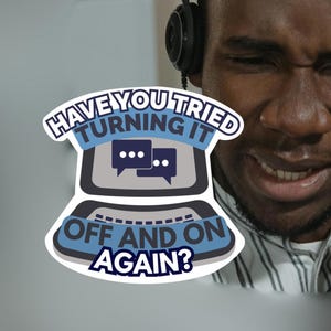 Puede incluir: Una persona con auriculares con una expresión frustrada. Una pegatina con el texto "¿Has probado a apagarlo y volverlo a encender?" está en primer plano. La persona está en un entorno de oficina.