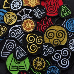 Può includere: Una collezione di toppe ricamate con vari simboli e disegni. Le toppe rotonde sono disponibili in una varietà di colori, tra cui nero, bianco, giallo, rosso, blu e verde. I disegni includono vortici, fiori e forme geometriche.