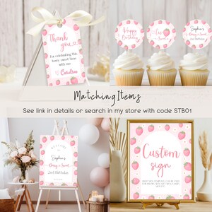 K&ouml;nnte beinhalten: Ein Set mit druckbaren Partydekorationen f&uuml;r einen zweiten Geburtstag mit Erdbeer-Motiv. Das Set beinhaltet ein Willkommens-Schild, ein individuelles Schild, Cupcake-Topper und ein Dankesch&ouml;n-Etikett. Die Dekorationen sind in einem rosa und wei&szlig;en Farbschema mit Erdbeeren und Blumen gehalten.