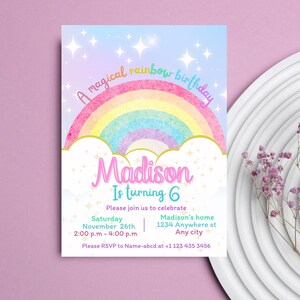 May include: A colorful rainbow birthday invitation with a watercolor effect. The invitation features a rainbow with a gold outline, clouds, and sparkling stars. The text "A magical rainbow birthday" is written in a whimsical font. The name "Madison" is written in a pink font with a gold outline. The text "Is turning 6" is written in a blue font. The invitation includes details for the birthday party, including the date, time, and location. The text "Please RSVP to Name-abcd at +1 123 435 3456" is written at the bottom of the invitation.