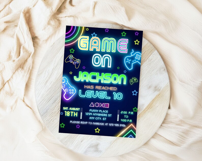 以下が含まれることがあります： 暗い青色の背景にネオン風の招待状。「GAME ON JACKSON HAS REACHED LEVEL 10」のテキストは、ネオンの緑と青のアクセントで表示されます。コントローラーのグラフィックとイベントの詳細が含まれています。