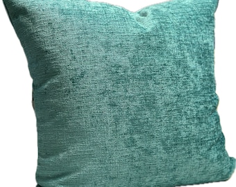 May include: A teal blue throw pillow with a textured fabric. The pillow is made of a soft, plush material and has a square shape.