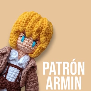 Op de afbeelding: Een gehaakte amigurumi-pop van een personage met blond haar, die een bruin jasje en een wit shirt draagt. De pop heeft blauwe ogen en een droevige uitdrukking. De tekst "PATRÓN ARMIN" is in witte letters op een beige achtergrond geschreven.
