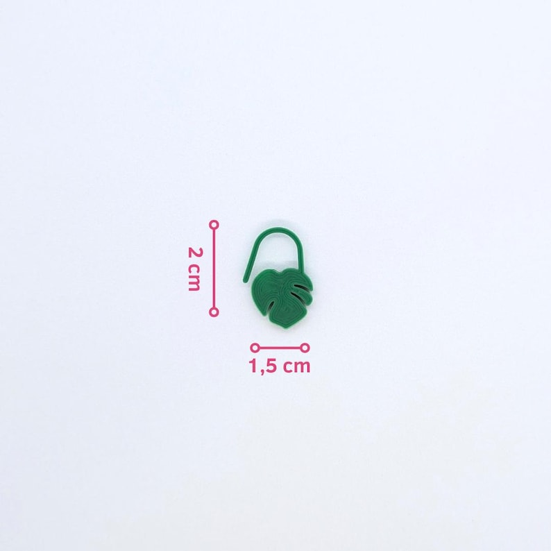 Puede incluir: Un marcap&aacute;ginas verde con forma de hoja, de 2 cm de alto y 1,5 cm de ancho, con una parte superior curvada. El marcap&aacute;ginas es de color verde liso y tiene un dise&ntilde;o detallado de hoja. El fondo es blanco.