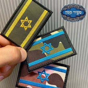 Può includere: Tre toppe ricamate con la Stella di David. Una è verde oliva con strisce gialle e una stella dorata. Le altre due hanno un motivo mimetico con strisce blu e una stella blu.