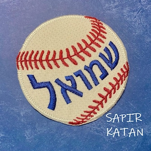 May include: White baseball with red stitching and blue Hebrew lettering that reads "Sapir Katan".