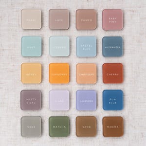 May include: Sixteen square color swatches in various pastel shades, including pearl, mint, and lavender. Each swatch has a color name printed in white. The swatches are arranged in a grid on a neutral linen background.