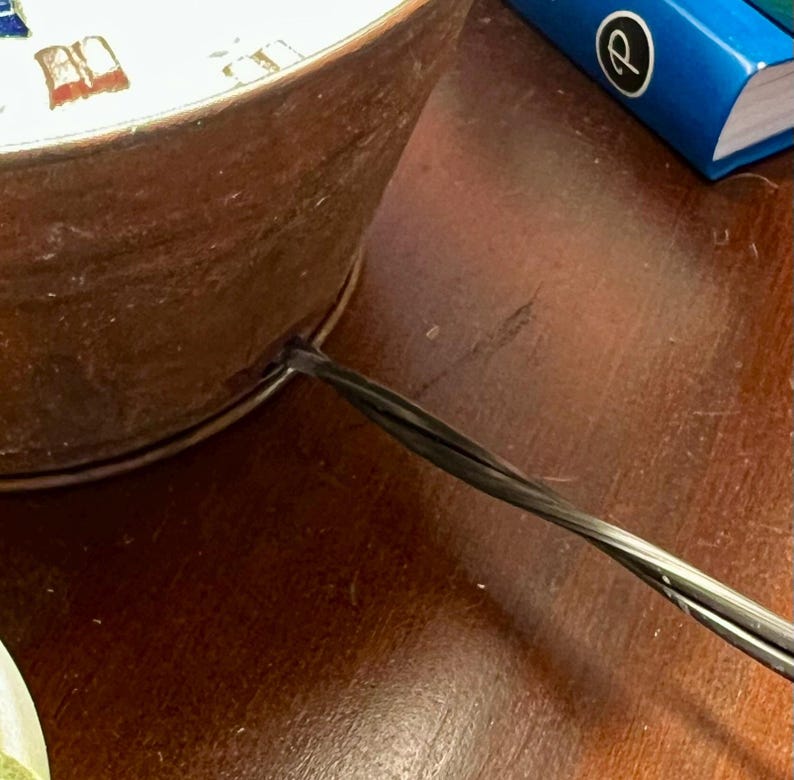 May include: A close-up of a copper-colored metal lamp base with a black electrical cord attached to the bottom.