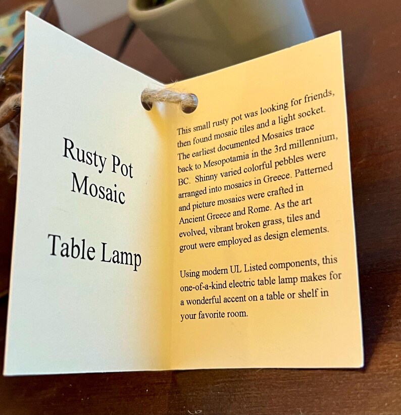May include: A rusty pot table lamp with a mosaic design. The lamp is made with modern UL Listed components. The tag reads "Rusty Pot Mosaic Table Lamp" and describes the history of mosaics.