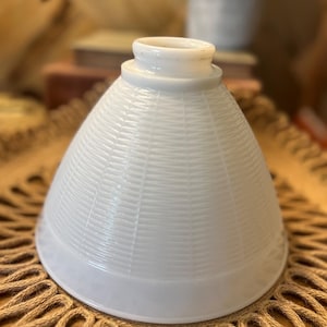 May include: White glass lampshade with a textured, woven pattern. The lampshade has a conical shape with a wide base and a narrower top. The shade is made of a solid white material.