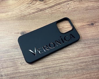 May include: Black phone case with a cut-out for the camera lens and the name "Veronica" printed in silver lettering.