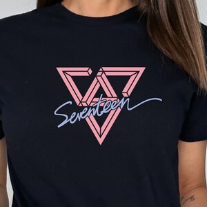 May include: Black t-shirt with a pink and black geometric triangle logo and the word "Seventeen" written in a cursive font.