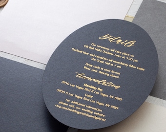 Op de afbeelding: Een zwarte ovale kaart met gouden letters met details over de huwelijksceremonie en receptie. De tekst luidt "Details", "De ceremonie vindt plaats op 1 oktober om 17:30 uur", "De cocktailreceptie en receptie vinden direct daarna plaats in The Great Hall om 19:00 uur", "Dresscode is semi-formeel", "Draag je dansschoenen!" en "Accommodaties", "Mandalay Bay", "3950 Las Vegas Blvd S Las Vegas NV 89109", "Luxor", "3900 S Las Vegas Blvd Las Vegas NV 89109", "Voor meer informatie kunt u onze trouwwebsite bezoeken: remp.com/weddings/ashleyandgabriel"