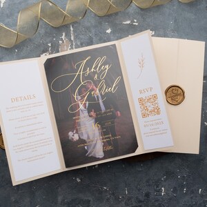 May include: A wedding invitation with a gold and white colour scheme. The invitation features a photograph of a couple in a woodland setting. The text on the invitation reads "Ashley & Gabriel".