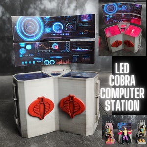 May include: A white, 3D printed Cobra computer station with red Cobra logos and blue LED screens. The station has a hexagonal base and is labelled "LED Cobra Computer Station".