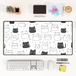 May include: A white and black mouse mat with a repeating pattern of cute cartoon cats. The cats are drawn in a simple, minimalist style and are all facing forward. The mouse mat is perfect for adding a touch of whimsy to any desk.