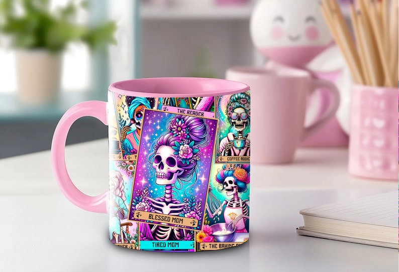 May include: Pink ceramic mug with a colorful design featuring a skeleton with flowers in its hair. The design includes the text "Blessed Mom" and "Tired Mom".