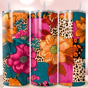 Op de afbeelding: Drie tumblers met bloemenpatroon en rietjes. De ontwerpen hebben een patchwork van levendige kleuren, waaronder oranje, roze, teal en luipaardprint. Grote bloemen en bladeren zijn prominent aanwezig, wat een gedurfde en kleurrijke esthetiek creëert. De tumblers zijn ontworpen voor koude dranken.