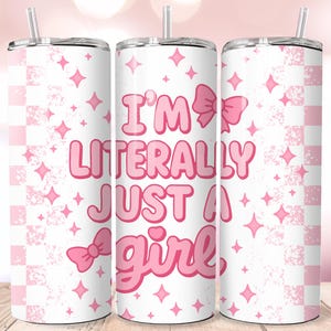 May include: A white tumbler with a pink and white checkered pattern and the text "I'M LITERALLY JUST A girl" in pink. The design includes pink bows and diamond shapes. The tumbler has a silver straw.