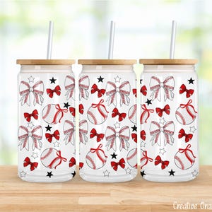 Könnte beinhalten: Drei transparente Glasbecher mit Bambusdeckeln und Strohhalmen. Jeder Becher hat ein Baseball-Design mit roten Schleifen, Basebällen und Sternen. Die Becher stehen auf einer Holzoberfläche.