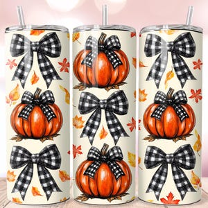 May include: Three stainless steel tumblers with a fall theme. Each tumbler features a cream background with orange pumpkins, black and white checkered bows, and autumn leaves. The tumblers have a straw and a lid.